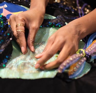 two hands play with pearls and beads inside of an imagined underwater creature made out of textiles