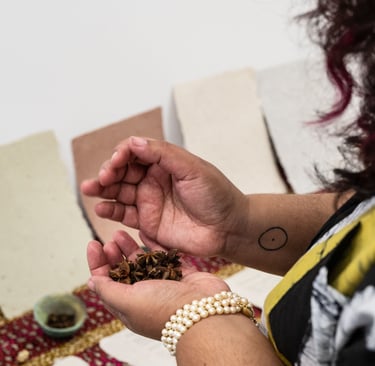 A woman holding a handful of star anise in front of handmade spice paper