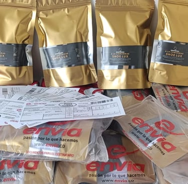 Gold packaging bags for Shoe Lux footwear stacked with Envia shipping envelopes and delivery.