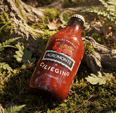 Bottiglia di Salsa Pronta di Ciliegino Agromonte con Etichetta della Terra in ambiente naturale