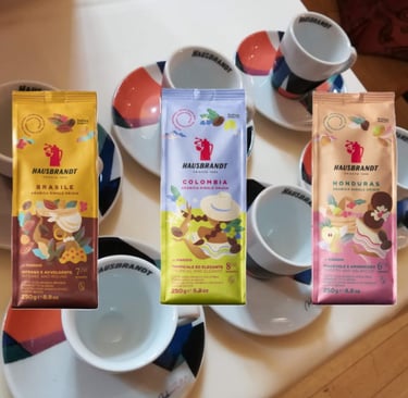 Confezioni Hausbrandt monorigine accanto a tazzine da espresso