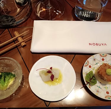 Piccoli assaggi serviti al tavolo del ristorante Nobuya Milano con tovagliolo ricamato Nobuya e mise en place