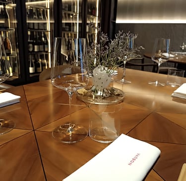Sala del ristorante Nobuya Milano con tavolo apparecchiato e cantina a vista sullo sfondo