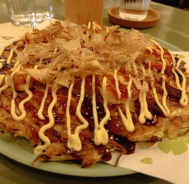 Okonomiyaki giapponese con salsa e scaglie di bonito servito da Maido