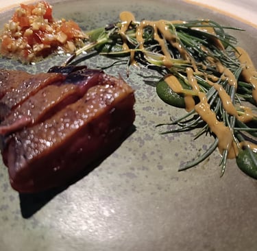 Dettaglio di una portata del Grow Restaurant con carne, erbe aromatiche e salsa vegetale