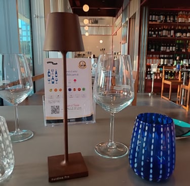 Sala del Bistrot Pedol Porta Nuova con tavoli affacciati sulle vetrate e cantina sullo sfondo