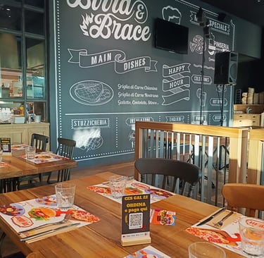 Interni del Birra & Brace con parete illustrata dedicata alle specialità del locale.