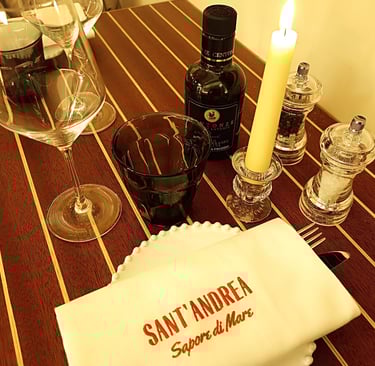 Tavolo apparecchiato al ristorante Sant’Andrea con tovagliolo ricamato e bottiglia di olio Centonze