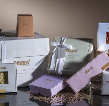 Confezioni e prodotti natalizi del brand Muzzi, parte del Gruppo IDB, rappresentativi della pasticceria italiana di qualità.