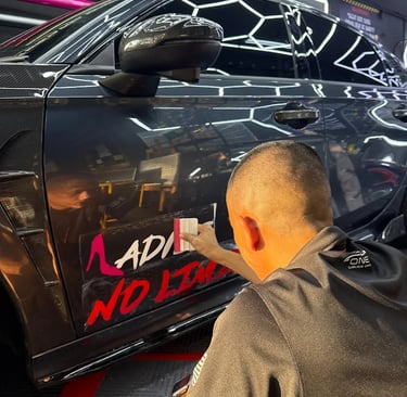 Technician applying custom pink lettering decal on car door panel