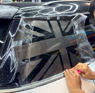 Technician installing Union Jack decal wrap on car rear window