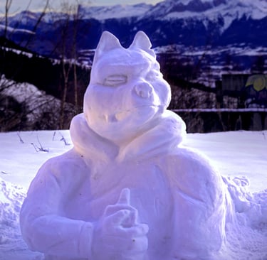 A creative snow sculpture of a cartoon character with mountain peaks in the background.
