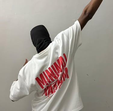 A person in a black balaclava wears an oversized white t-shirt with red streetwear graphics.