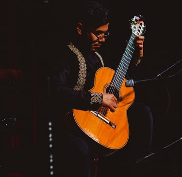 A musician performing a classical flamenco guitar solo on stage during a live concert.