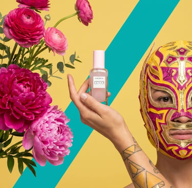 A person in a lucha libre mask holding Glow Recipe Dew Drops serum next to pink peonies.