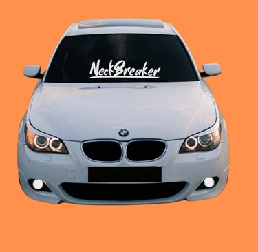 White modified BMW E60 with Neckbreaker windshield decal and halo headlights on orange background.