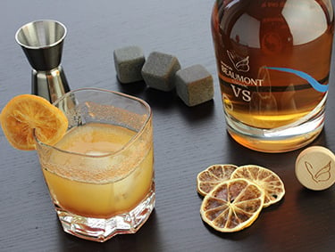 Cocktail cognac Maison Beaumont VS Sunrise servi sur glace avec agrume séché