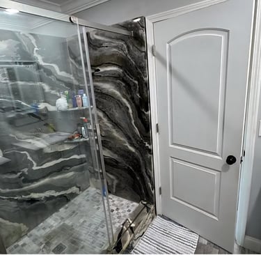 Modern walk-in shower with black and white marbled stone panels and glass doors.