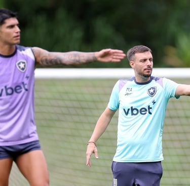 Botafogo soccer coach directing a training session with players on a grass field.