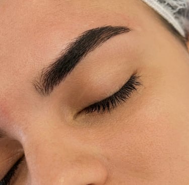 Close-up of a woman's face showing professional microblading eyebrow shaping and eyelash extensions.