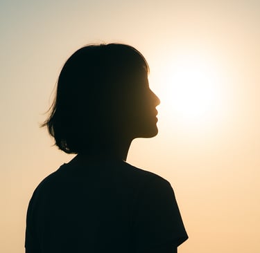 Imagen de perfil de una mujer.El sol está atrás de ella, no se nota su cara pero parece en reflexión