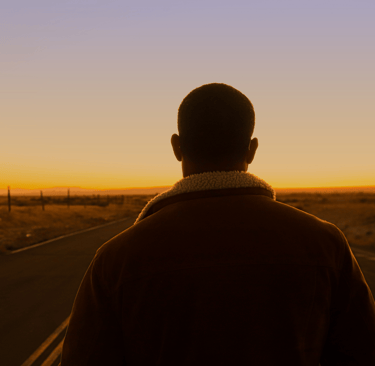 Joven mirando a lo lejos en una carretera mientrás reflexiona acerca de lo que busca en la vida