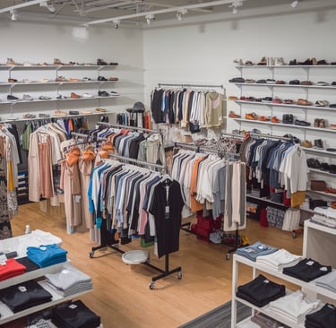 Modern clothing store interior with organized racks of casual and formal wear, neatly folded apparel.