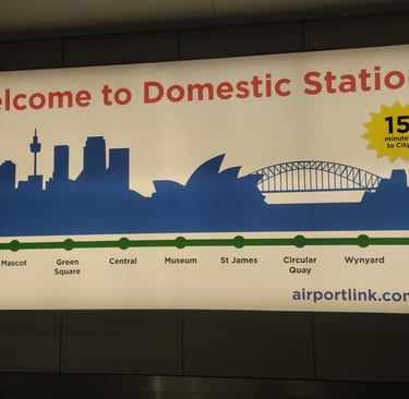 A bright sign at Sydney’s Domestic Station welcomes travelers, featuring a skyline illustration with iconic landmarks