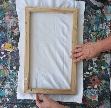 a person holding a picture frame over a fabric
