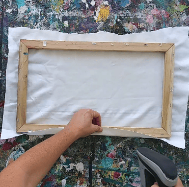 a person folding a piece of fabric over a frame