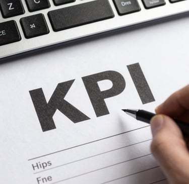 A person pointing a pen at the KPI text on a business report next to a computer keyboard.
