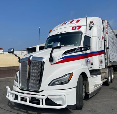 Camión refrigerado AFH Logistics con logotipo rojo y azul estacionado en pavimento