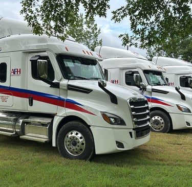 Flota de camiones AFH Logistics alineados en un campo verde en Allende, Nuevo León