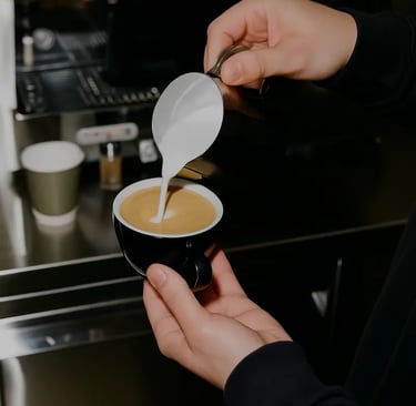 Barista preparando café espresso en taza negra con máquina de café de fondo