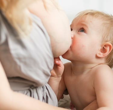 a baby is being fed by a woman in a gray dress