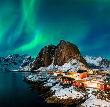 Green Northern Lights aurora borealis over a snowy fishing village in Lofoten Islands, Norway.