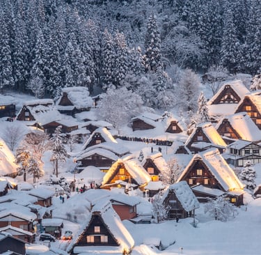 Snow-covered Shirakawa-go village at night with glowing traditional gassho-zukuri farmhouses in Japan.