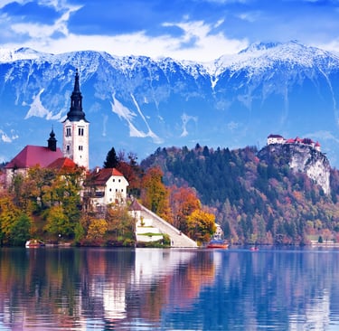 Scenic Lake Bled in Slovenia featuring the Pilgrimage Church on Bled Island with snow-capped Julian Alps.