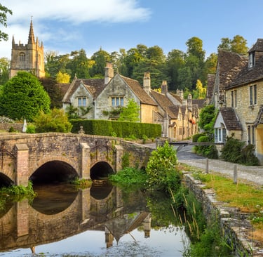 A stone arch bridge over a river in the picturesque English village of Castle Combe, Cotswolds.
