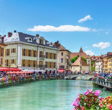 Picturesque Annecy, France canalside with colorful buildings, bustling restaurants, people, and historic architecture under
