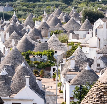 Panoramic view of traditional white trulli houses with conical stone roofs in Alberobello, Puglia, Italy.