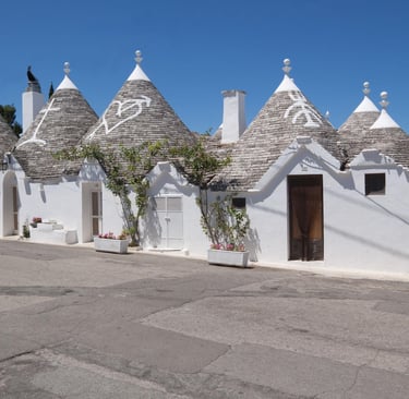 Traditional white trulli houses with conical stone roofs in Alberobello, Puglia, Italy.