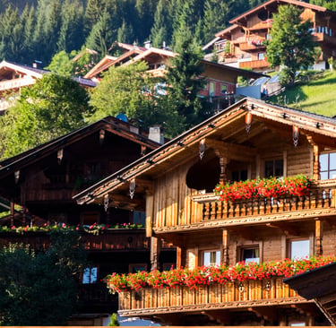 Traditional wooden Swiss chalets with red flower boxes nestled on a lush green mountain slope.