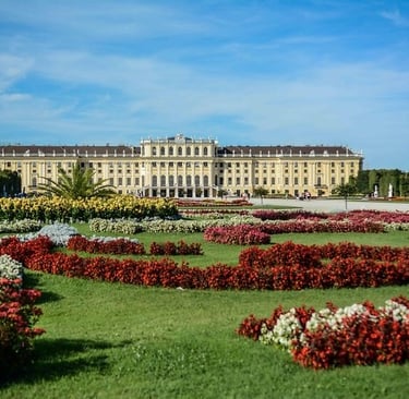 Schonbrunn Palace in Vienna with vibrant flower gardens under a clear blue sky.