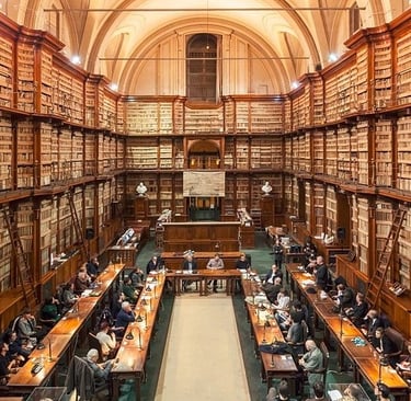 People studying at long tables inside the historic Casanatense Library with massive wooden bookshelves.