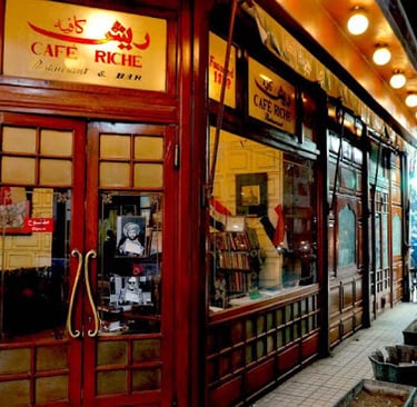 The historic wooden facade and entrance of Cafe Riche restaurant and bar in downtown Cairo at night.