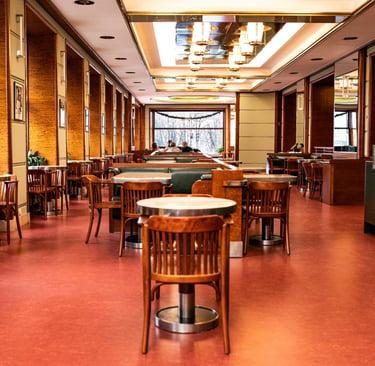 Elegant cafe interior with wooden chairs, red flooring, and modern lighting fixtures.