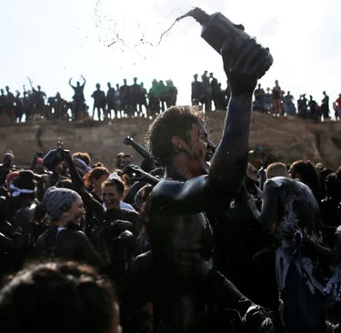 Crowd of festival participants covered in black mud at the Boryeong Mud Festival in South Korea.
