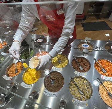 A staff member adds dried ingredients to a custom ramen cup at the Cup Noodles Museum's My Cupnoodles Factory.