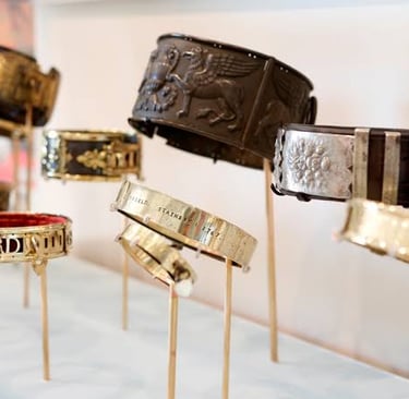 A collection of antique leather and metal dog collars with intricate engravings displayed on stands.